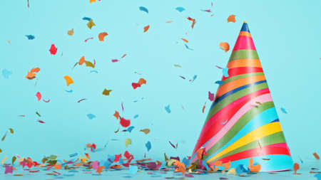 Colored confetti and party hat on blue background