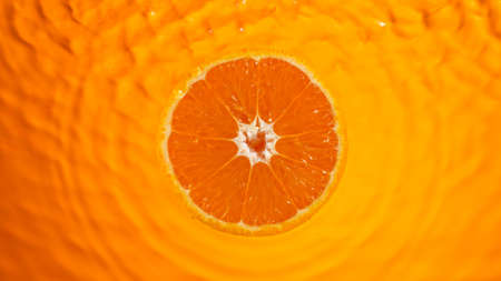 Fresh orange slice falling into splashing water splashingの写真素材