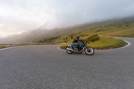 Motorcycle driver riding in Alpine landscape.