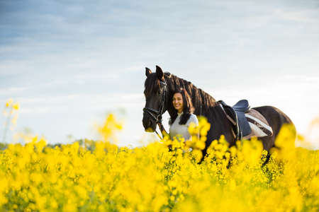 Young woman with her horse in evening sunset light.の写真素材