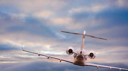 Private jet plane flying above clouds in beautiful sunset.の写真素材