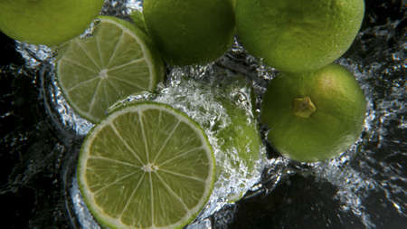 Fresh limes falling into water, freeze motion.