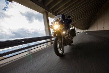Motorbiker riding in Austrian Alps, dramatic sky. Travel and freedom, outdoor activitiesの写真素材