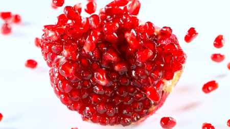 Fresh pomegranate pieces falling, white backgroundの写真素材