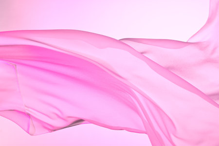Closeup of rippled pink silk fabric, color fabric draped in soft waves empty bed sheetの写真素材