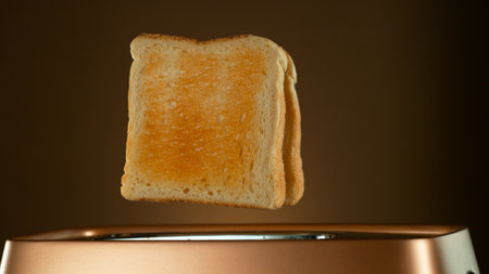 Crispy Golden Toasts Jumping out of Toaster on Bronze Gradient Backgroundの写真素材