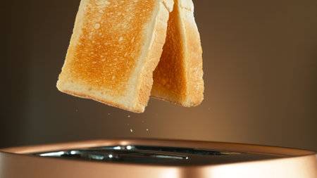Crispy Golden Toasts Jumping out of Toaster on Bronze Gradient Backgroundの写真素材