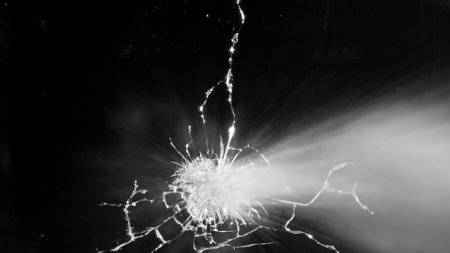 Close-up of gunshot through the glass, shattering against the black backgroundの写真素材