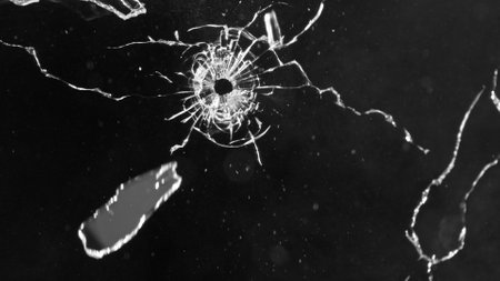 Close-up of gunshot through the glass, shattering against the black background