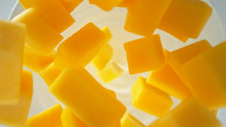 Fresh mango pieces falling into yoghurt cream, top down viewの写真素材