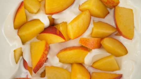 Fresh nectarines pieces falling into yoghurt cream, top down viewの写真素材