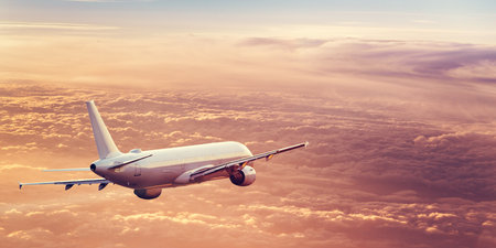 Passengers commercial airplane flying above clouds in sunset light. Concept of fast travel, holidays...