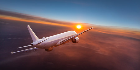 Passengers commercial airplane flying above clouds in sunset light. Concept of fast travel, holidays and business.の写真素材