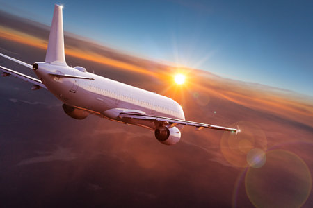 Passengers commercial airplane flying above clouds in sunset light. Concept of fast travel, holidays...