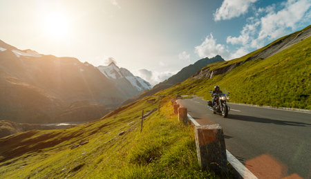 Motorbiker riding in Italian Alps during sunrise, dramatic sky. Travel and freedom, outdoor activitiesの写真素材