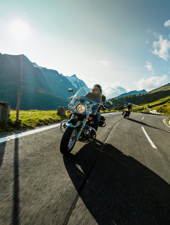 Motorbiker riding in Italian Alps during sunrise, dramatic sky. Travel and freedom, outdoor activitiesの写真素材