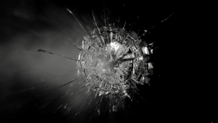 Close-up of shot through the glass, shattering against the black backgroundの写真素材