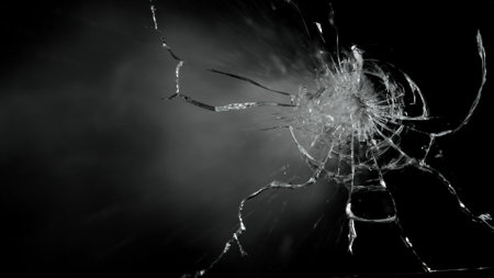 Close-up of gunshot through the glass, shattering against the black backgroundの写真素材