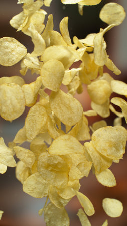 Freeze motion of flying fried potatoes chips on gradient yellow background