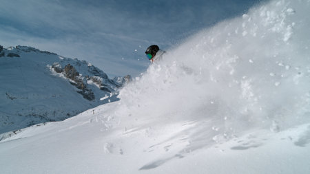 Snowboard rider riding down fresh powder during sunny day , Alpine sceneryの写真素材