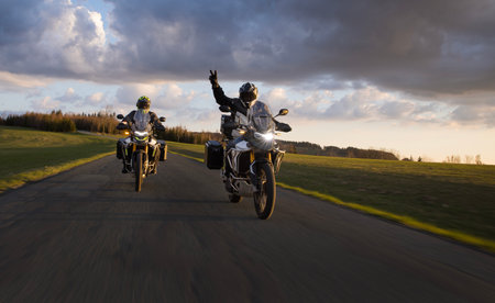 Drivers riding motorcycle on empty road during sunset, spring mountainsの写真素材