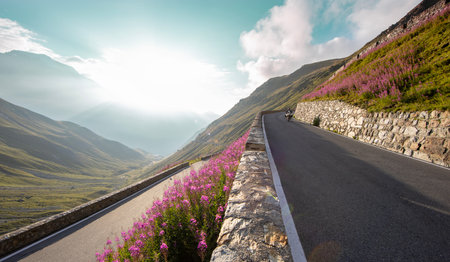 Motorcycle rider riding in Italian Alps during sunrise, dramatic sky. Travel and freedom, outdoor activitiesの写真素材
