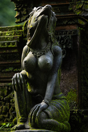 Monkey sculpture fully covered with green moss in Ubuds Monkey Forest. Bali, Indonesia.