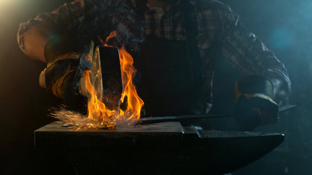 Close-up of blacksmith forging glowing hot iron on anvil with flying sparksの写真素材