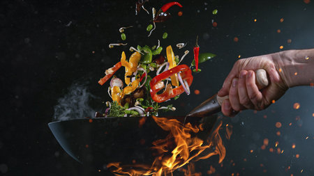 Freeze Motion of Flying Asian Meal with Vegetable and Prawns into Wok Panの写真素材