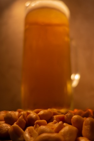 glass of light cold frothy beer, nuts on an old wooden tableの写真素材