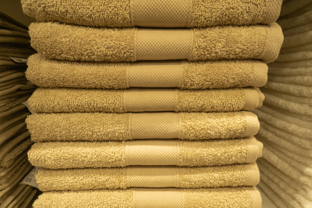 Two stacks of colorful bath towels with hyacinth flower on light background. Pastel colors cotton towels. Hygiene, fabric,spa and textile concept. White, beige, pink and blue towels are neatly folded on the shelf.の写真素材