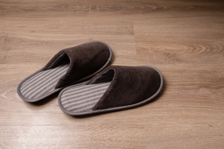 Brown men's slippers stand on the oak floorの写真素材