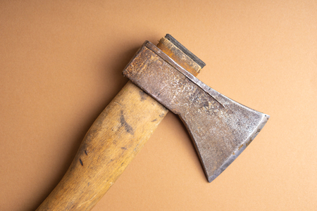 The old ax lies on the ground . Old ax with wooden handle on light brown background. Top view.の写真素材