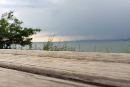 Storm clouds over the sea and the city. Old wooden bench against the background of the sea