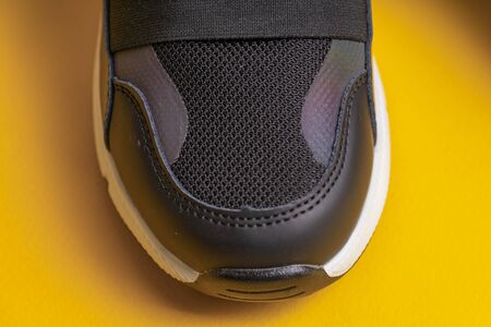 Sock black childrens school sneakers with  on a yellow background