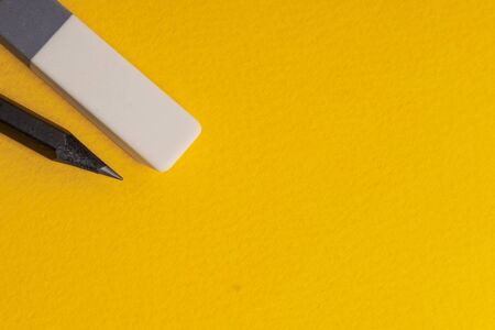 Black drawing lead pencil and eraser on a yellow background. Copyspace