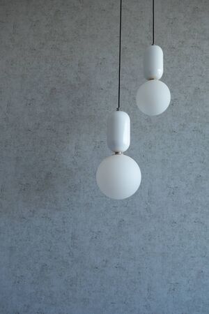 The structure of concrete is gray. Creative vintage background. Structural plaster. Modern lights in the form of a white ball on a long wireの写真素材