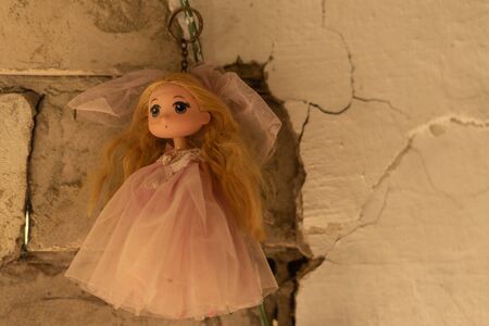 A doll in a wedding dress is hanging on an old cracked wall. Mystery, horrorの写真素材