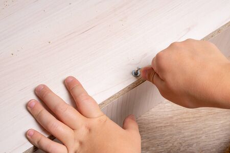Hands of a craftsman assembling wood chipboard furniture. Tightening SCREW.の写真素材