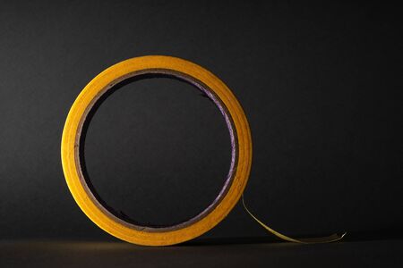 Roll of masking tape. Yellow tape. On a black background