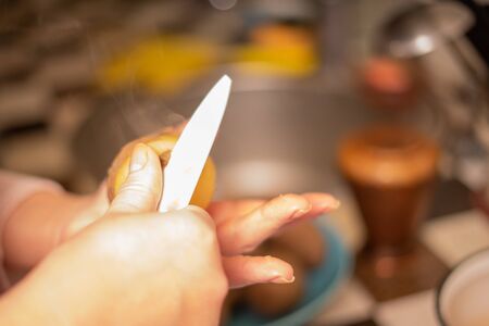 Female hand peeling potatoes with a white knife. Selective focusの写真素材
