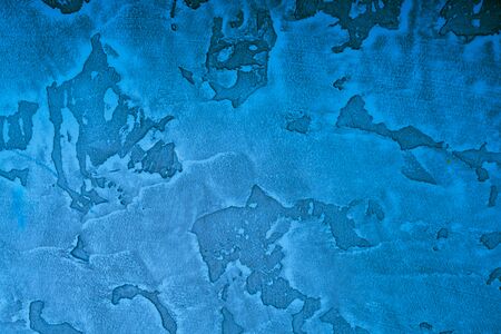 Structural stucco in classic blue. Creative vintage background. Contrasting stains on the wall