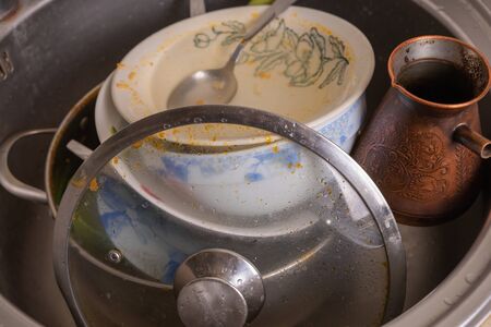 A mountain of unwashed utensils in a kitchen sink. Desolation and messの写真素材