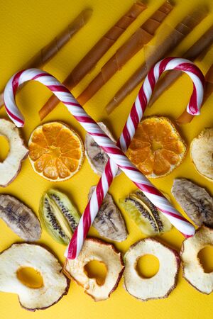 Peppermint candy canes with dried fruits on a yellow backgroundの写真素材