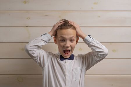 A fair-haired boy of 10 years in a white shirt with the self-tie bow tie smiles against the...