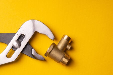 Bronze Check Valve. Non-return valve for water in the electric water heater system. On a yellow background. Universal Adjustable Wrenchの写真素材