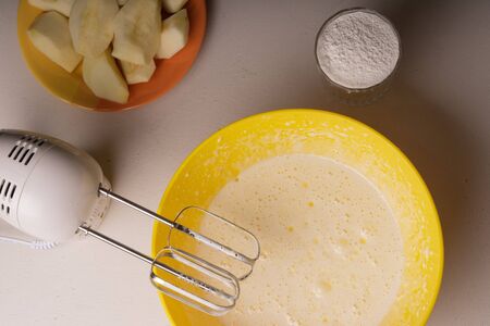 A woman mixes the ingredients for a pie in a yellow bowl with an electric mixer