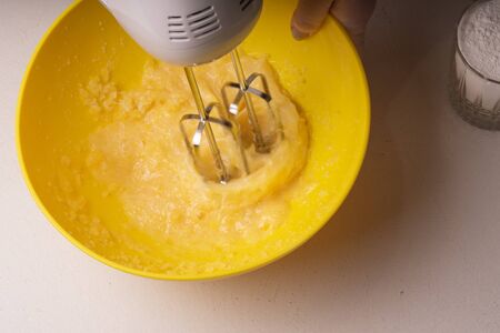 A woman mixes the ingredients for a pie in a yellow bowl with an electric mixer
