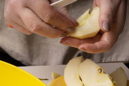 Hands of an elderly woman peeling an apple with a white ceramic knifeの写真素材