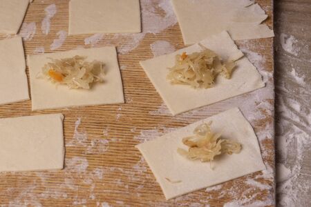 A rectangular piece of dough with cabbage - for making ravioli dumplings. Plywood cutting board,...